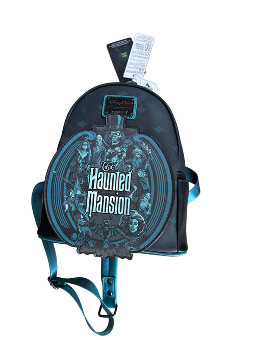 A Loungefly Disney Haunted Mansion mini backpack in black with teal accents and a large circular graphic print, shown on a wooden floor with its tags attached.